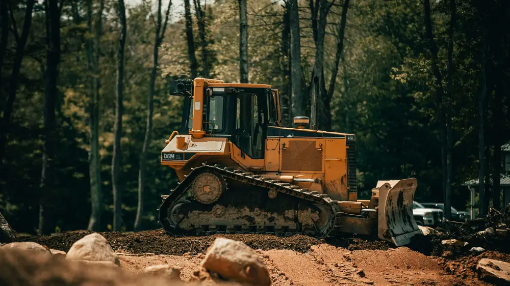 Bulldozer grading dirt among pine trees
